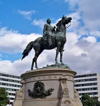 George Henry Thomas equestrian statue on a stone pedestal with a star emblem, with city buildings behind it.