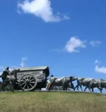 Monument to the Cart sculpture showing a covered cart pulled by oxen with a rider on horseback nearby.