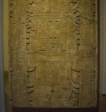 Detail of the Raimondi Stela showing a stylized anthropomorphic figure with an ornate headdress and patterned staffs.