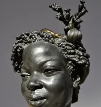 Bust of Woman from the French Colonies with curled hair and a floral headdress.