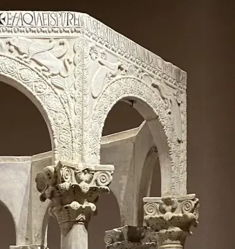 Carved stone arches and ornate columns from the Baptistry of Callistus, with reliefs of birds, foliage, a cross, and an inscription.