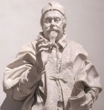 Marble bust of Clemente X wearing an ornate ecclesiastical garment, with a cap, rosary, and book.