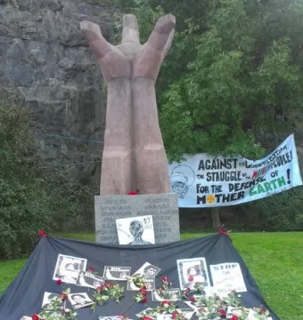 La Mano sculpture with red roses and photographs at its base