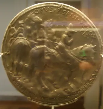 Medal of John VIII Palaiologos showing a round gold-colored relief with figures on horseback and inscriptions around the edge.