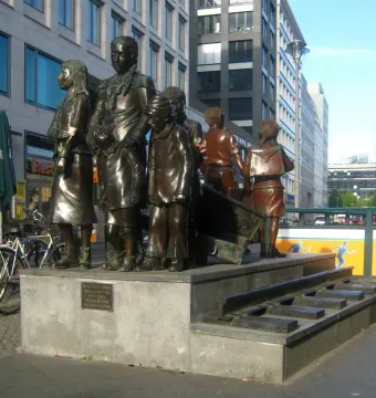 The Trains to Life – Trains to Death memorial with bronze child figures on a stone platform and railway tracks leading down the steps.