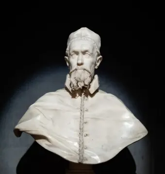 White marble bust of Pope Innocent X on a pedestal against a dark background.