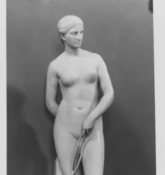 Marble statue of a nude woman standing on a round base and holding a looped rope.