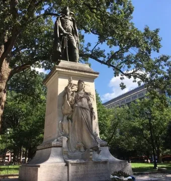 Commodore John Barry statue atop a tall stone pedestal with a Victory relief in a park