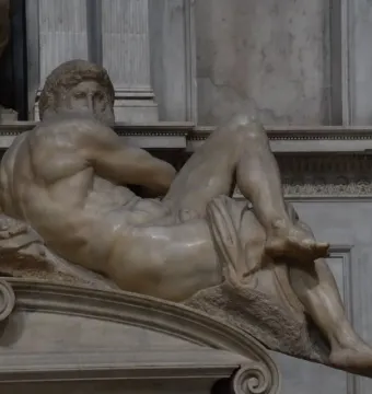 Michelangelo’s Day, a reclining marble male figure with drapery over the lower body.