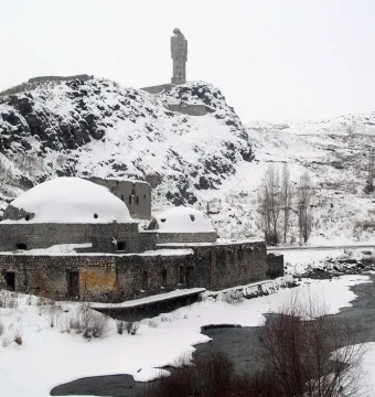 Statue of Humanity on a snowy rocky hill, showing two slender figures facing each other with their arms reaching toward the center.