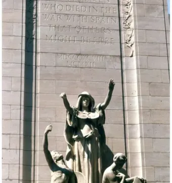 USS Maine National Monument with three allegorical figures below an inscribed stone wall.