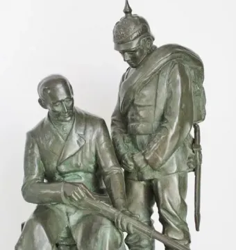 Dreyse Monument showing a seated man holding a rifle beside a standing soldier in a spiked helmet.