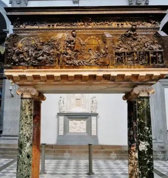 The Resurrection Pulpit with dark relief panels above two polished marble columns on a checkered floor.