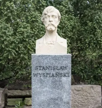 Stanisław Wyspiański bust on a speckled stone pedestal in a wooded outdoor setting