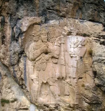 Ivriz relief showing two carved figures in a cliff face, including a larger figure holding grapes and a smaller figure with a staff.
