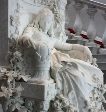 Sleeping Beauty marble sculpture of a reclining woman with closed eyes, set in an ornate flower-carved seat.