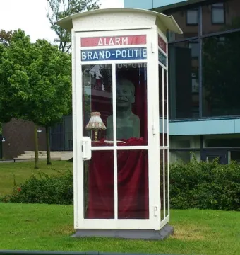A sculpted bust of Stalin displayed inside a white Dutch emergency booth with red and blue lettering.