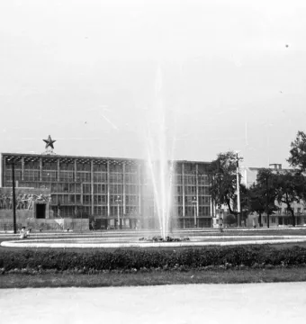 The Stalin Monument seen from behind, with a fountain and a star-topped building in the background.
