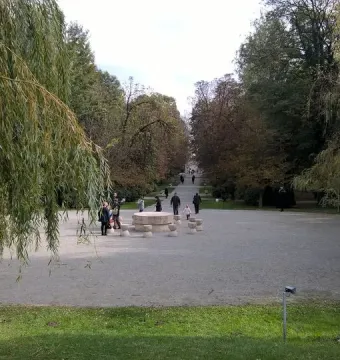 Table of Silence stone sculpture with round table and hourglass-shaped stools in a park lined with trees