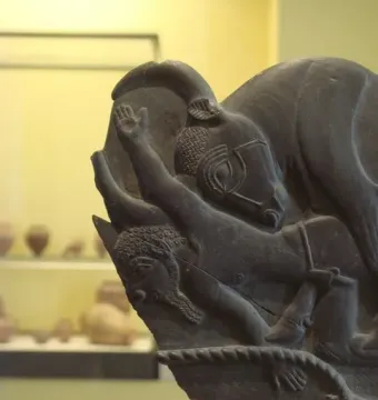 Bull Palette carved stone fragment showing a bull\'s head and forebody with a human figure reaching toward it.