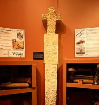 Padrão stone pillar with a cross top displayed in a museum exhibit.