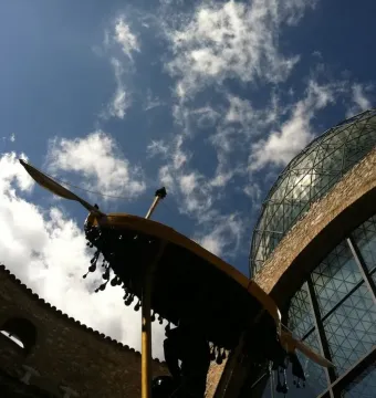 Rainy Taxi suspended between stone buildings and a glass dome under a blue sky.