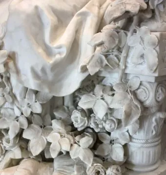 Sleeping Beauty marble sculpture detail with roses, drapery, and a spindle beside an ornate pillar.
