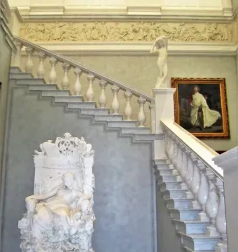Sleeping Beauty marble sculpture seated in an ornate armchair beside a grand staircase