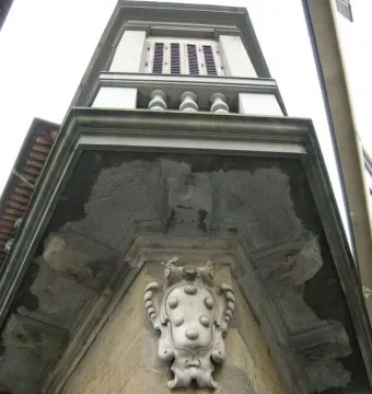 The Fontana dello Sprone corner with an ornate Medici shield carving on a stone building facade.