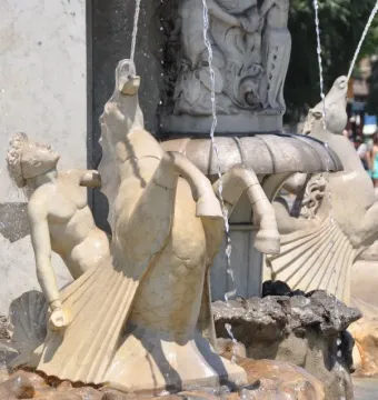 Lower section of the Genio Catalán Fountain with a winged figure and hippocampus sculptures flowing with water.