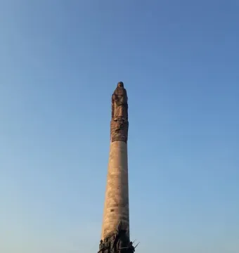 The Roundabout of the Disappeared monument with a tall stone column, statues at the top and base, and a banner reading \