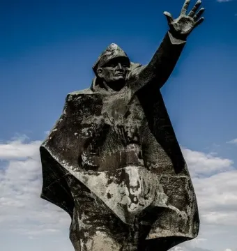 Kościuszkowców Memorial with a skateboarder performing a trick beside the bronze monument