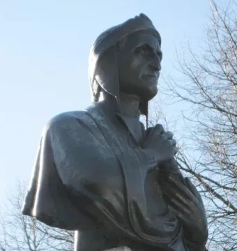 La mort de Dante sculpture shown in close-up, with a dark bronze figure in a cap and draped clothing against the sky.
