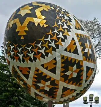 Vegreville pysanka egg sculpture with geometric black, gold, and white patterns outdoors.