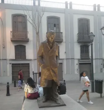 The Monument to César Vallejo, a bronze sculpture of a man in a long coat on a concrete plinth in a public plaza.