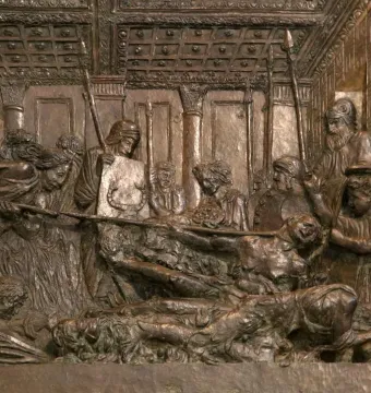 Bronze relief from The Resurrection Pulpit showing a crowded indoor scene with figures gathered around a central body.