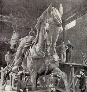 A giant equestrian statue of Victor Emmanuel II under construction in a workshop, with several men standing nearby.