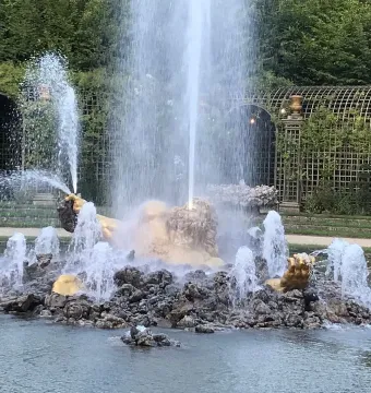 Enceladus Fountain with a golden statue rising from dark rocks as water jets spray around it.