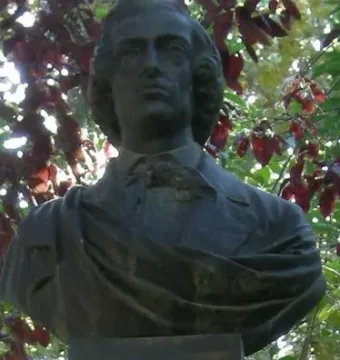 Frédéric Chopin bust with wavy hair above a mossy stone marker.