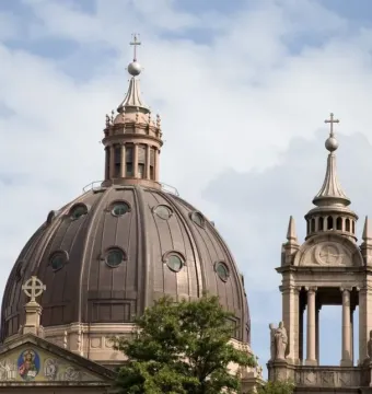 Monumento a Júlio de Castilhos beside a cathedral dome and tower under a cloudy sky.