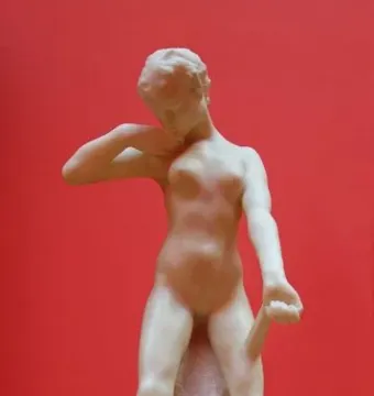 Standing Fauness, a pale nude female sculpture with her head bowed and one hand at her neck.