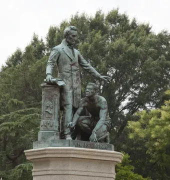 The Emancipation Memorial showing Abraham Lincoln standing over a kneeling man with broken shackles on a stone pedestal.