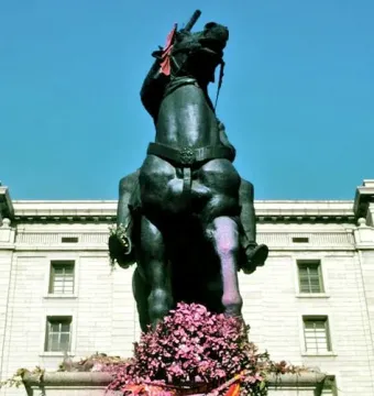 Equestrian statue of Francisco Franco on a stone pedestal with a flower wreath at the base.