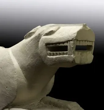 Leona de Baena stone sculpture shown in profile with a wide-open mouth and squared teeth.