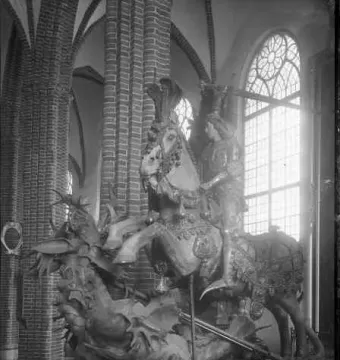 Saint George and the Dragon sculpture showing a knight on a rearing horse above a dragon inside a church interior.