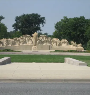 Fountain of Time stone monument with a central robed figure and smaller sculpted figures arranged in a wave-like form.