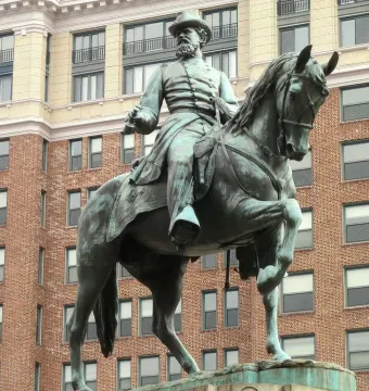 General James B. McPherson equestrian statue in bronze with a green patina, shown against a tall brick building.