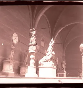 Judith and Holofernes sculpture on a tall pedestal in a grand arched hall with surrounding statuary.