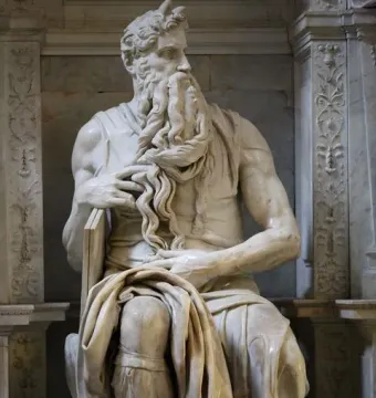 Michelangelo\'s Moses, a seated marble statue of a bearded man with horns holding tablets under his arm.