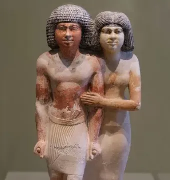 Painted ancient Egyptian statue of Raherka and Meresankh standing together on a rectangular base.
